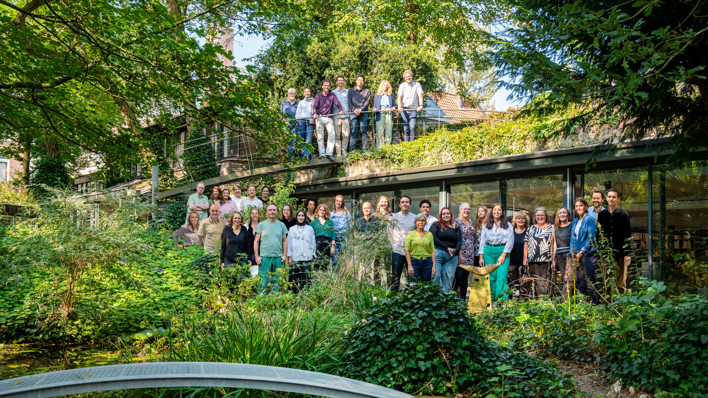 Photograph of the architects outside the studio, surrounded by greenery.