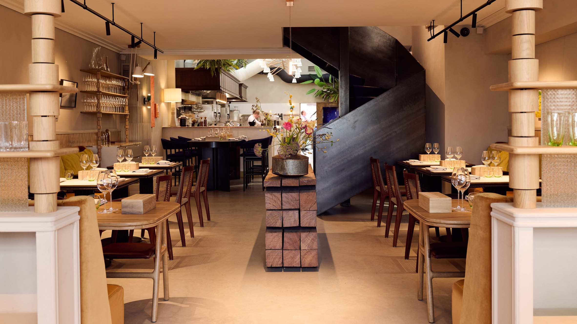 Photograph of a restaurant with a small central island and a geometric staircase in the far right of the image.